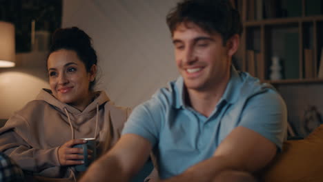 boyfriend turning on television sitting with woman at home late evening closeup.