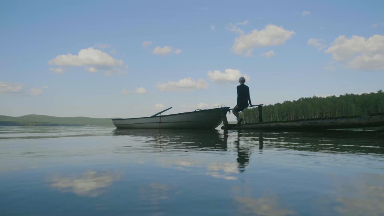 Person sitting on a dock by a calm lake