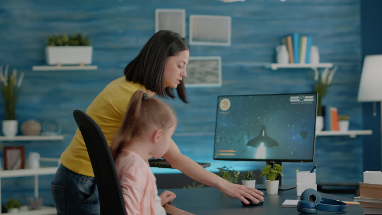 Young girl playing video games on computer while mom interrupting