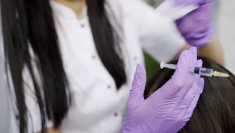an experienced cosmetologist disinfects the skin of head with the using of a sponge and begins to doing a procedure of mesotherapy in the center of cosmetology. close-up.