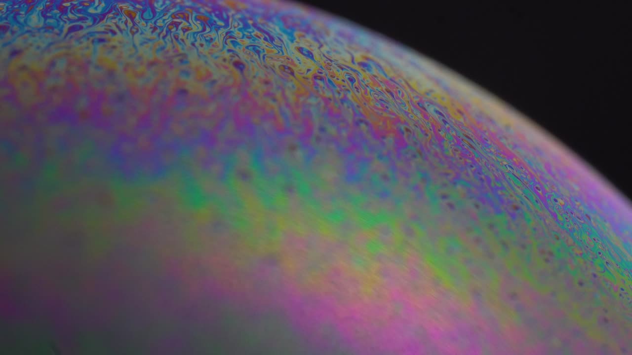 Abstract multicolor chaotic swirl texture inside soap bubble, frame. Slow motion.