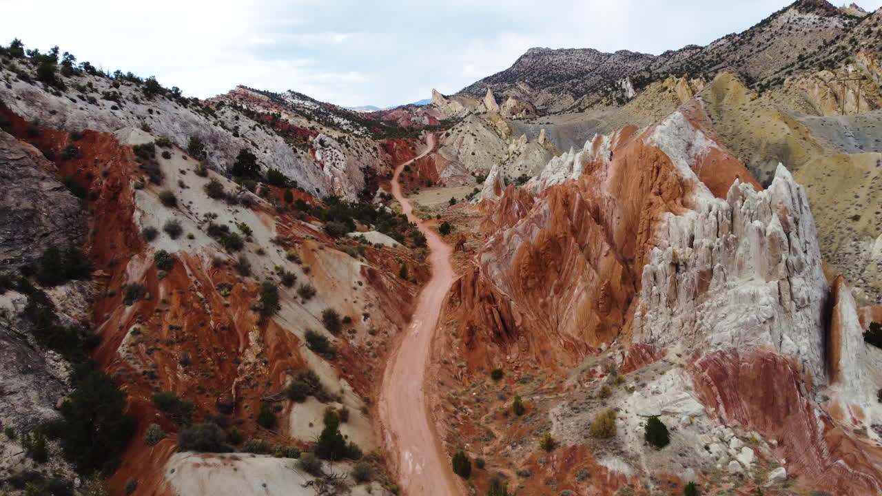 un camino en un valle estrecho en un macizo montañoso con colores ocres, cámara lenta, formaciones rocosas rojas únicas en utah