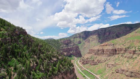 Wide-Open-Deep-Canyon-Gorge-Covered-In-Healthy-Green-Pine-Tree-Foliage-During-Bright-Hot-Summer-Day-With-Blue-Cloudy-Sky