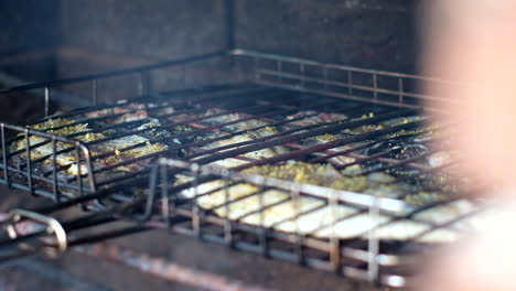 galjoen barbecue on grid over open fire with rising smoke, closeup rack focus