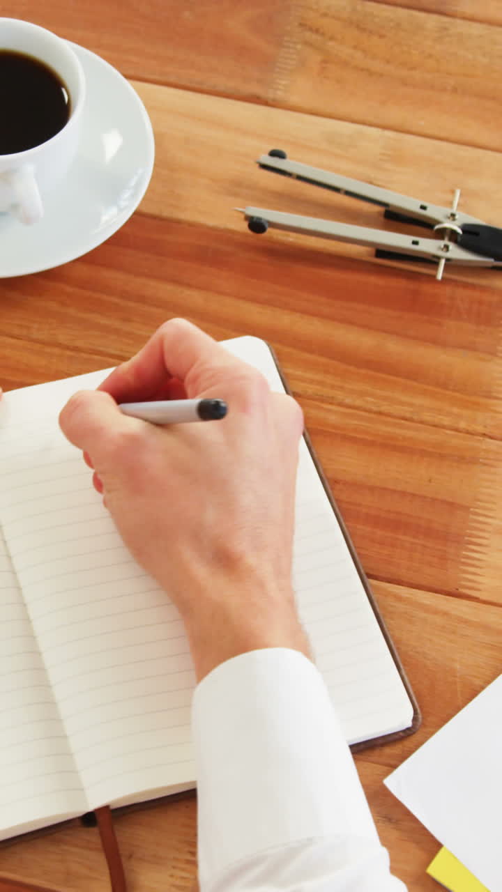 Businessman sitting at desk writing in diary