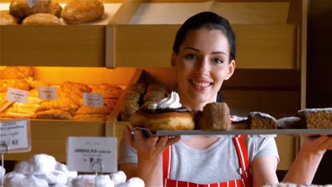 Portrait-of-female-baker-holding-sweet-food-in-tray