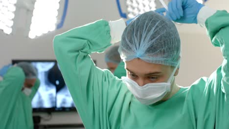 caucasian female surgeon wearing surgical gown and cap in operating theatre, slow motion