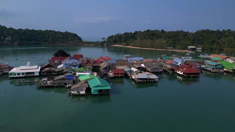 Bang Bao Pier floating village in Koh Chang island, Thailand, showing colorful houses and boats sailing in turquoise water. Stunning aerial view flight panorama overview drone