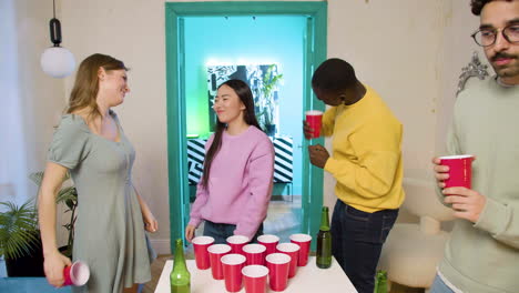 jóvenes amigos multiétnicos jugando pong de cerveza en casa