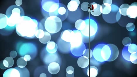 Weihnachtsmütze-über-Mikrofon-Vor-Lichtflecken-Vor-Blauem-Hintergrund