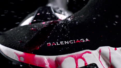 slow motion pouring water clean red syrup on waterproof black sneaker , close up
