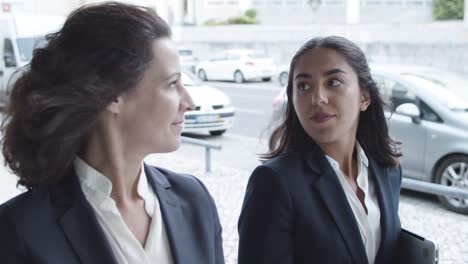 dolly shot of two serious business colleagues walking on city street, talking and discussing work projects 1