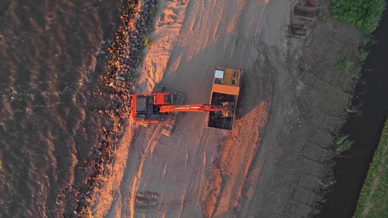Aerial View of Excavator Loading Rocks into Dump Truck at Sunset