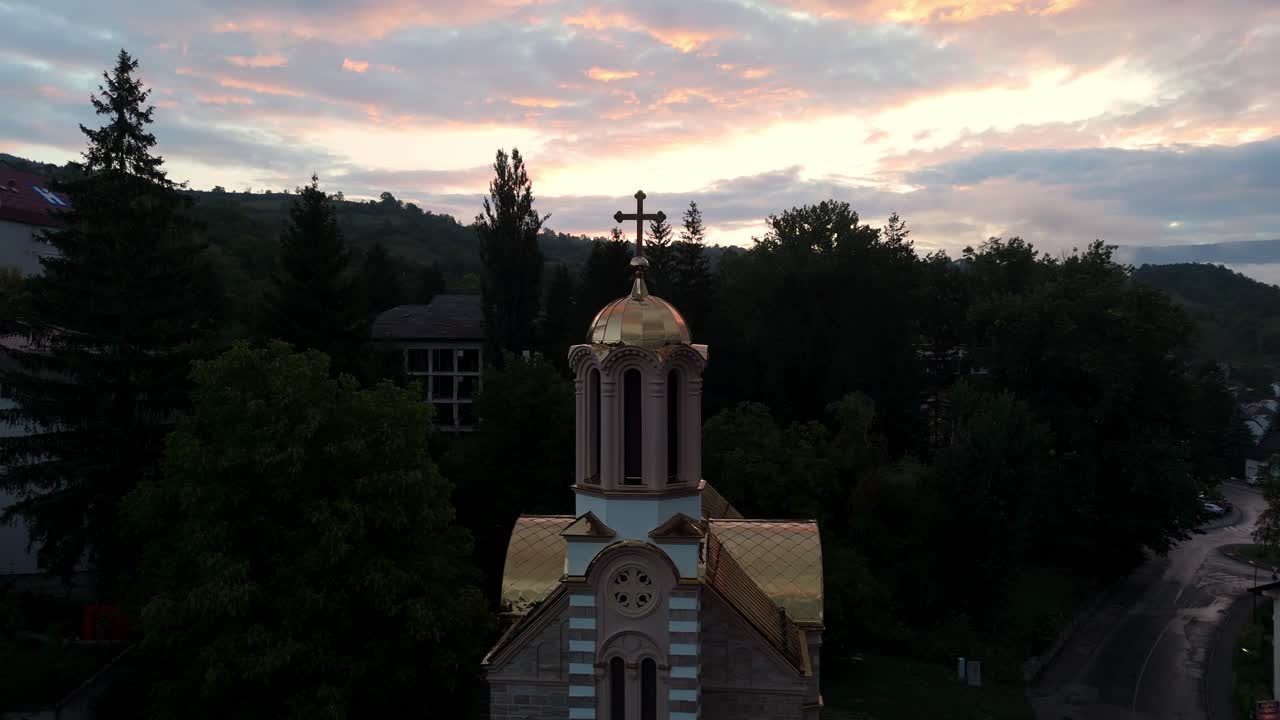 Aerial drone rotate around the Orthodox Church in Jajce, Bosnia and Herzegovina, surrounded by historic stone houses and green hills in the heart of the Balkans