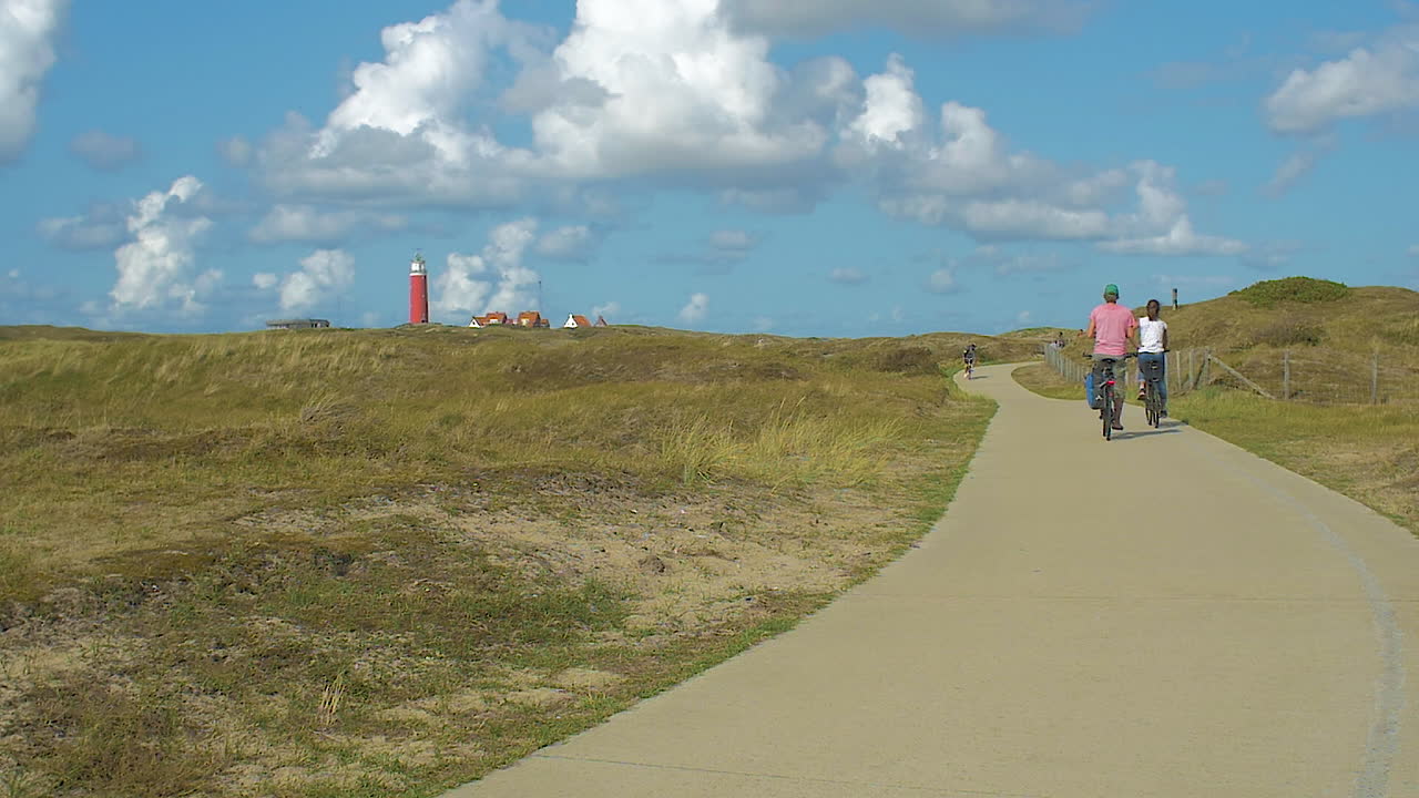 Couple Cycling on a Bike Path Towards a Lighthouse
