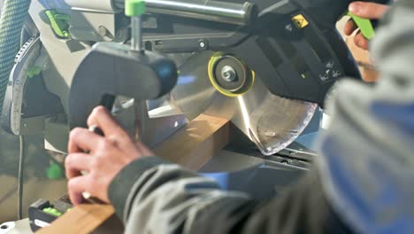 close-up of a man's hand working on a machine with a circular saw