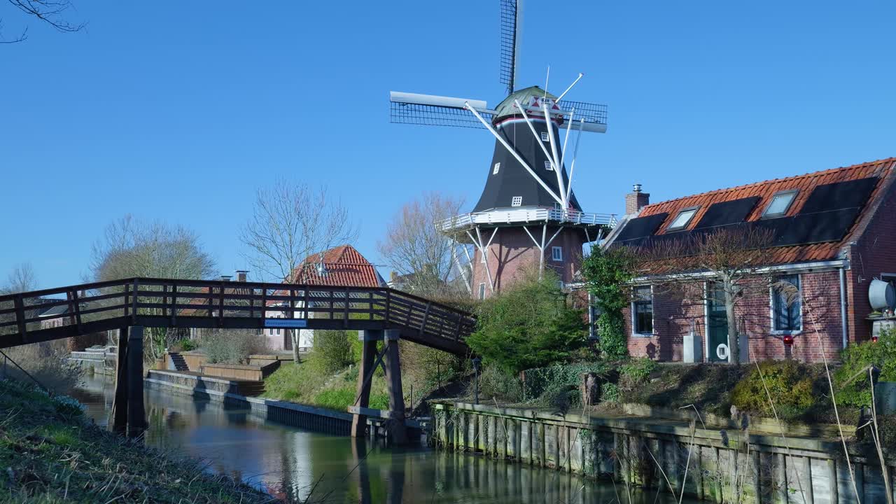 Traditionele Nederlandse windmolen en kanaal met houten brug op een zonnige dag