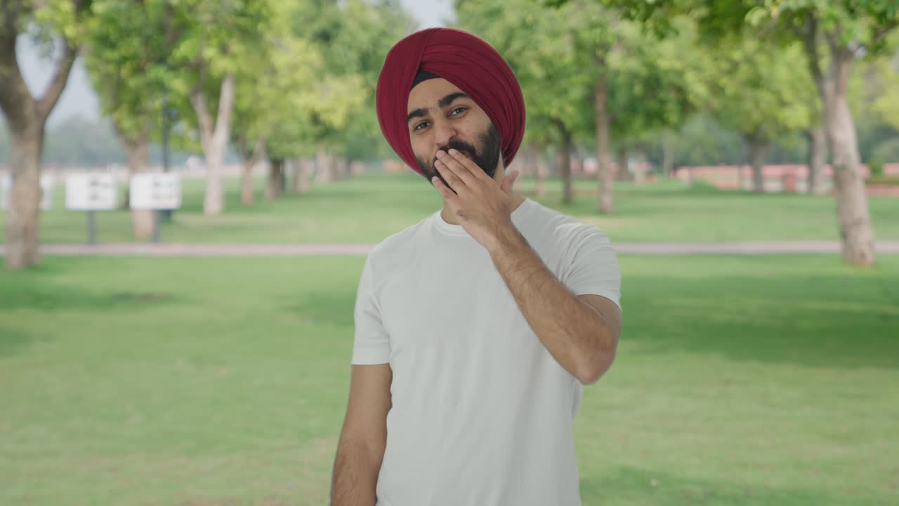 Uomo indiano sikh felice che manda baci volanti al parco