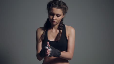 Young-beautiful-fit-woman-dusting-powder-on-her-hands-wrapped-in-boxing-tapes-as-she-prepares-for-a-workout-at-the-gym