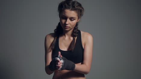 young beautiful fit woman dusting powder on her hands wrapped in boxing tapes as she prepares for a workout at the gym