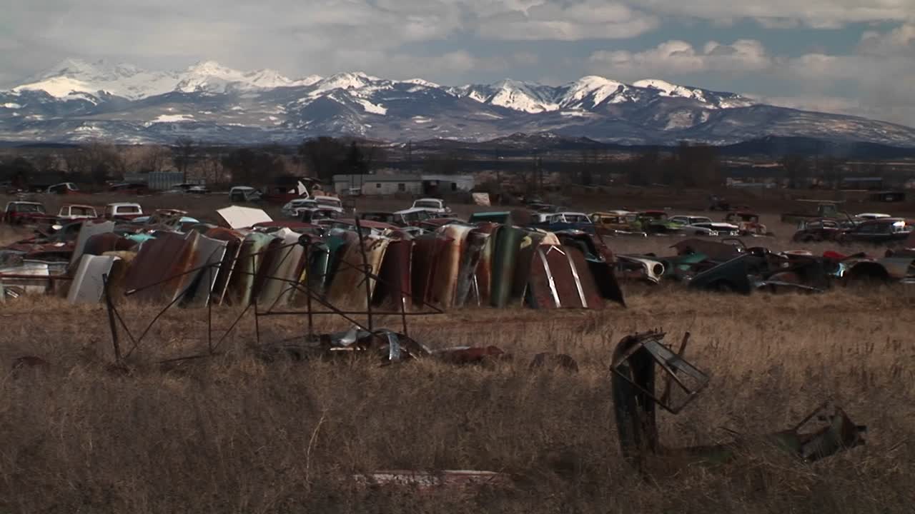 средний снимок автомобильной свалки на фоне живописных скалистых гор