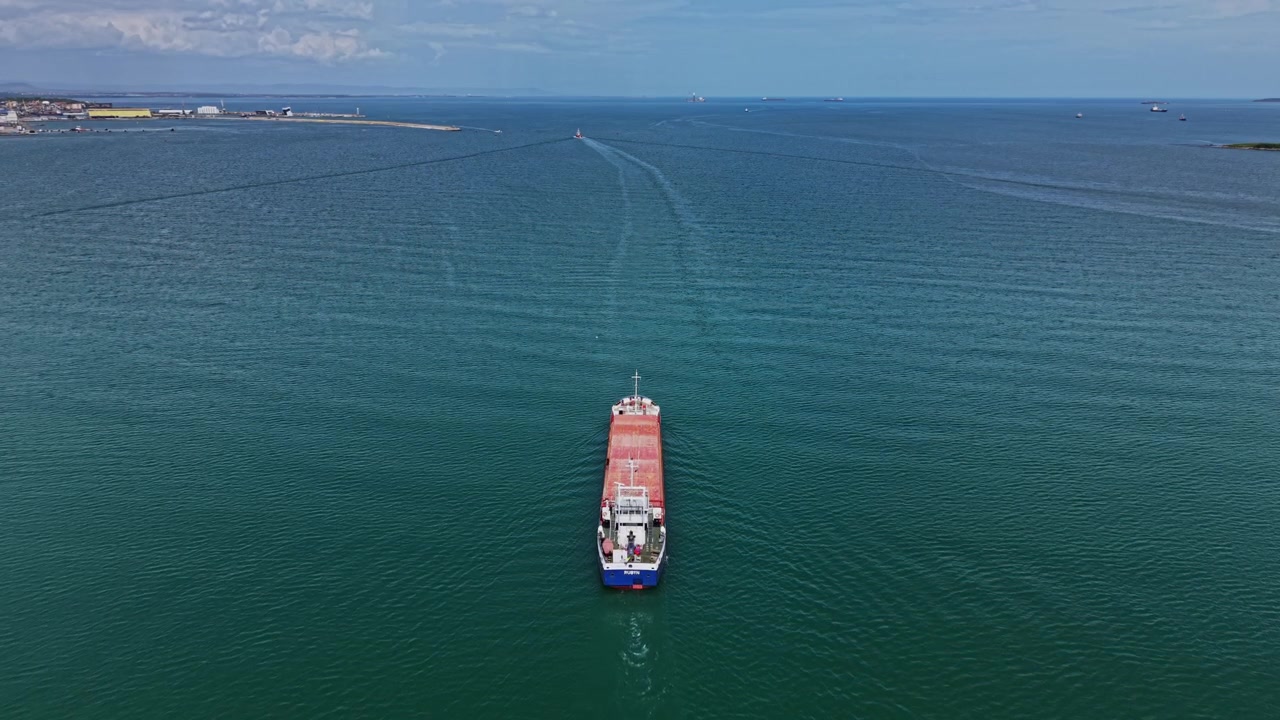 Buque de carga navegando sobre aguas tranquilas cerca de un puerto costero