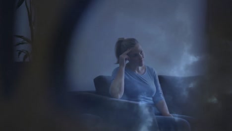 animation of caucasian woman sitting on couch at home over storm