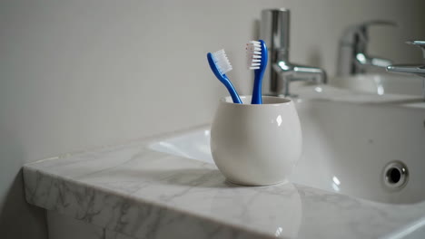 toothbrushes in a cup on a marble countertop