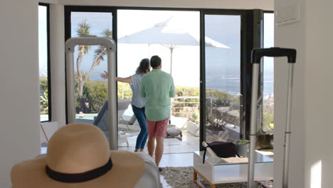 senior couple dancing joyfully in vacation home with ocean view in background