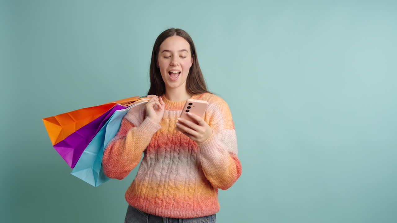 Happy woman with shopping bags and smartphone in studio