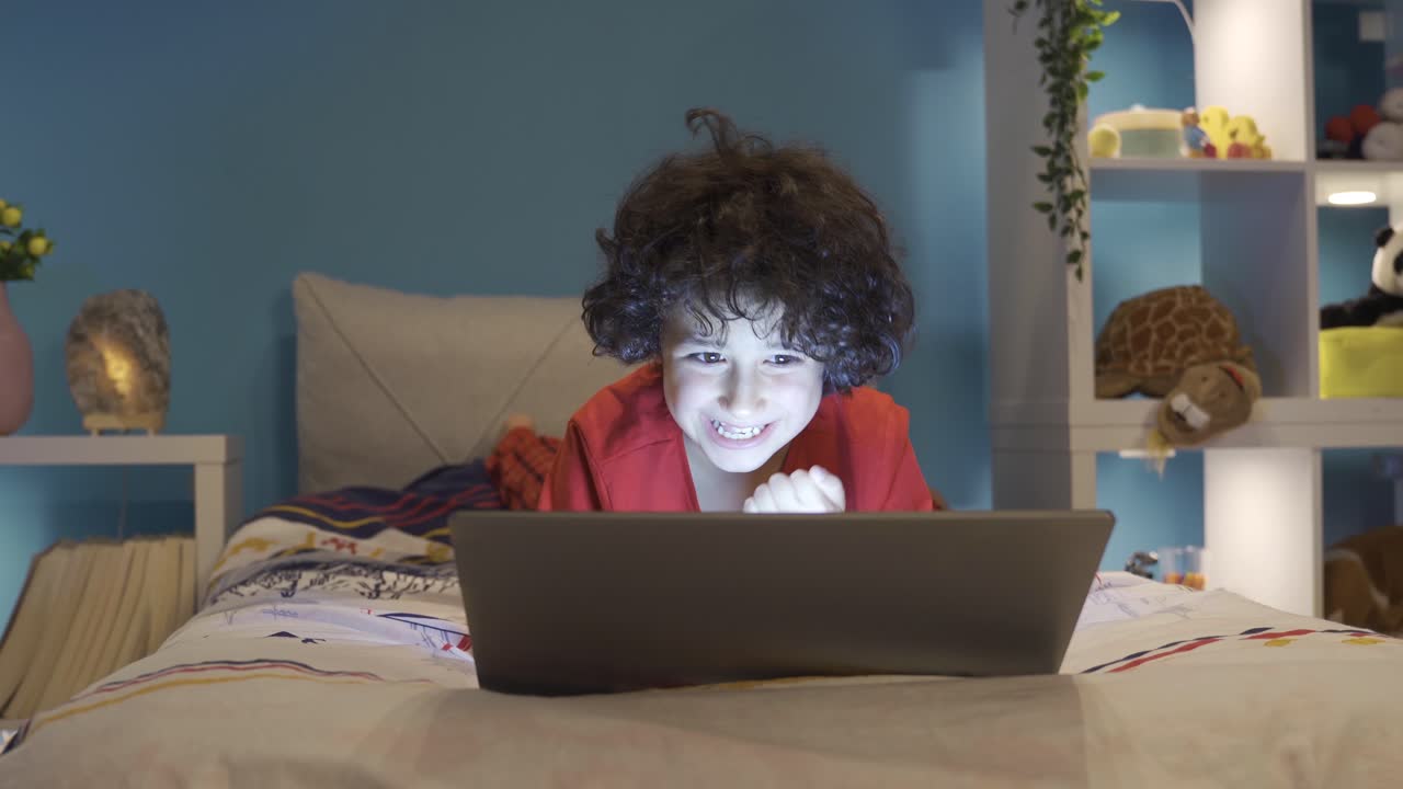 un niño adicto a los juegos jugando en su computadora portátil por la noche en su habitación.