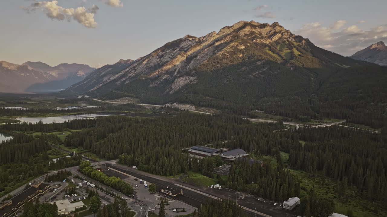 banff ab canada aerial v13 flyover estación de tren capturando el paisaje de valle boscoso y fenland a lo largo del río bow con las cadenas montañosas de norquay vistas al amanecer - filmado con mavic 3 pro cine - julio 2023