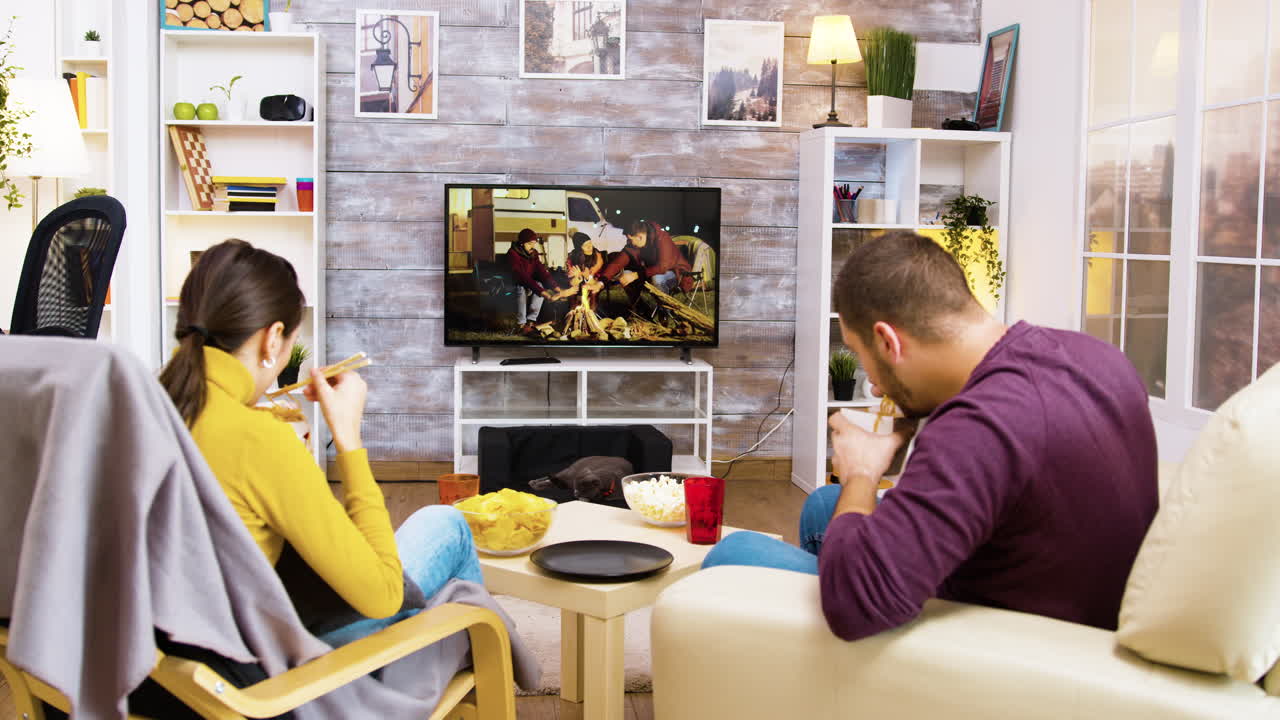 Couple Relaxing at Home Watching TV and Eating Snacks