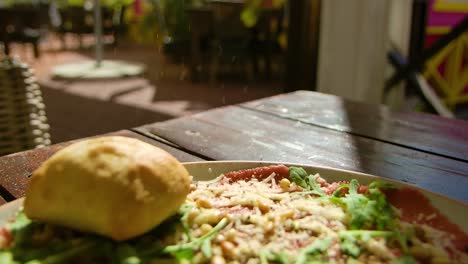 lento hacia atrás enfoque rack revelación de copos de pimienta cayendo en el plato con carpaccio