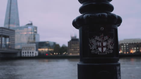 the emblem of the city of london on a lamppost and the shard in the background