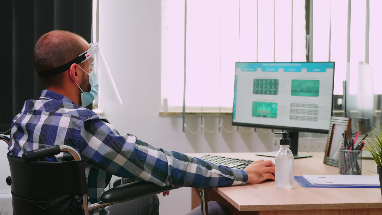 hombre discapacitado con máscara desinfectando las manos antes de trabajar