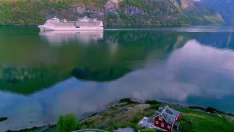 luxury cruise ship in the fjord near the village of flame, norway - aerial follow