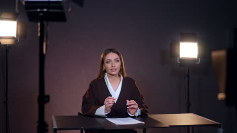 attractive caucasian woman with long brunette hair talks taking video. blogger works in studio filming video content.