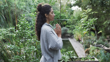 focused biracial woman practicing yoga in sunny garden, slow motion