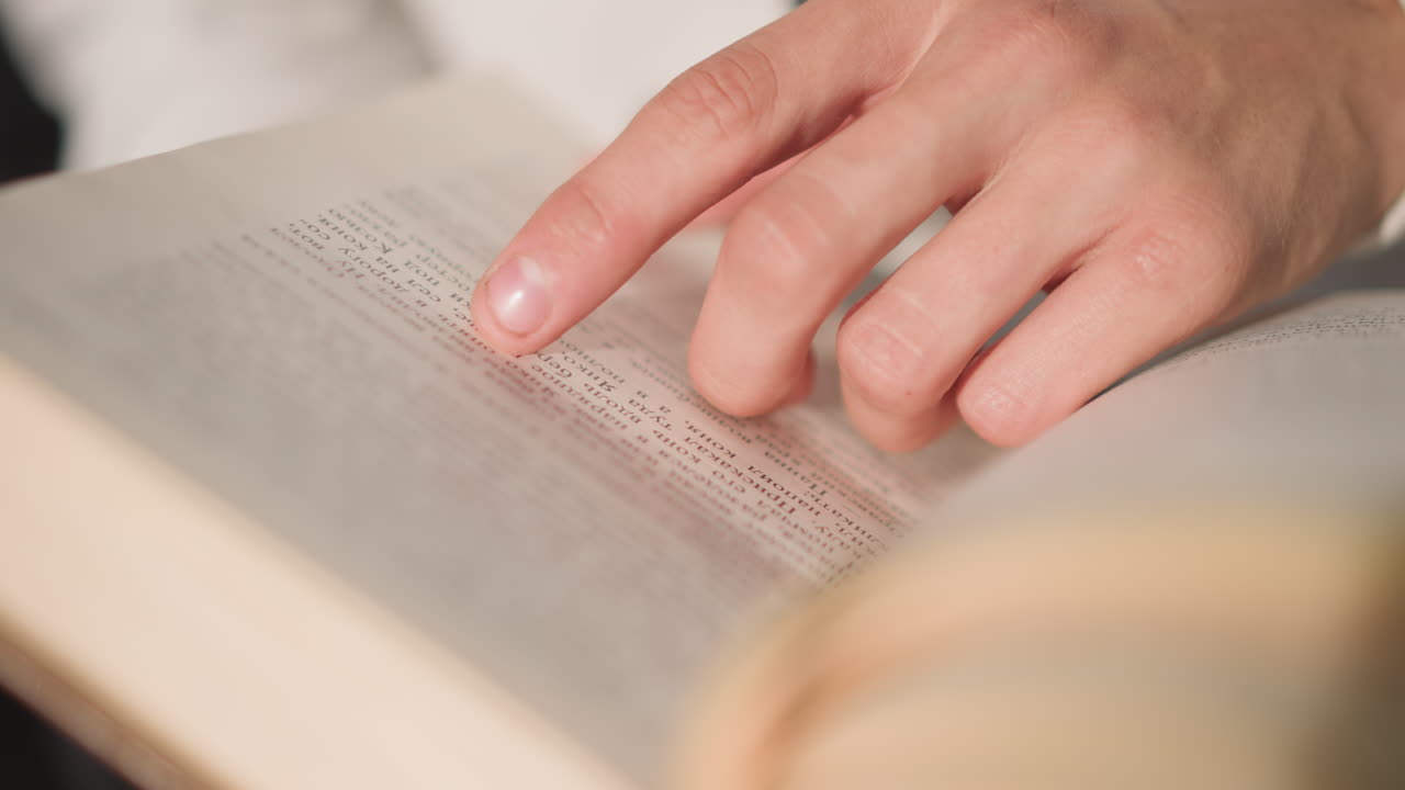 closeup hands tracing text in book, soft warm light, vintage hardcover, careful finger following lines, quiet focused study, subtle page texture and margin notes, slow turning motion, intimate
