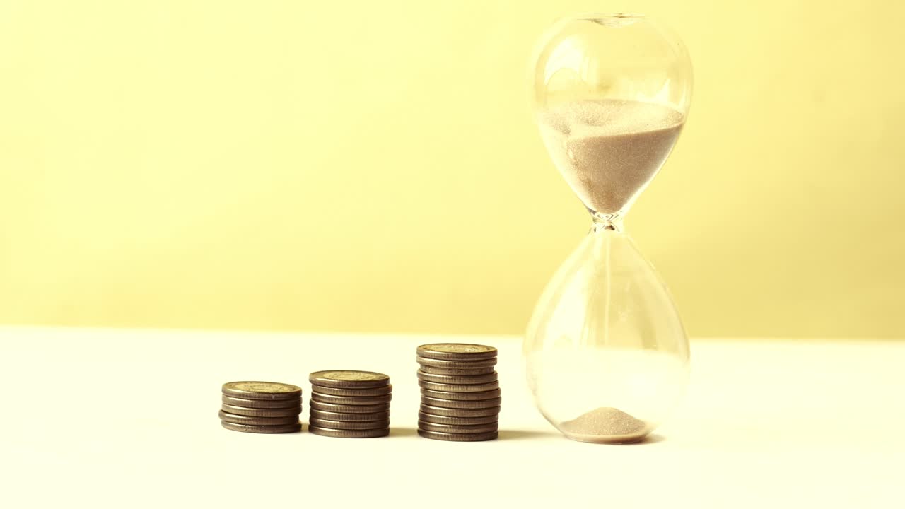 Hourglass on table, sand flowing through the bulb of sandglass