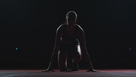 female athlete on a dark background to run the sprint of the cross country pad on the treadmill on a dark background