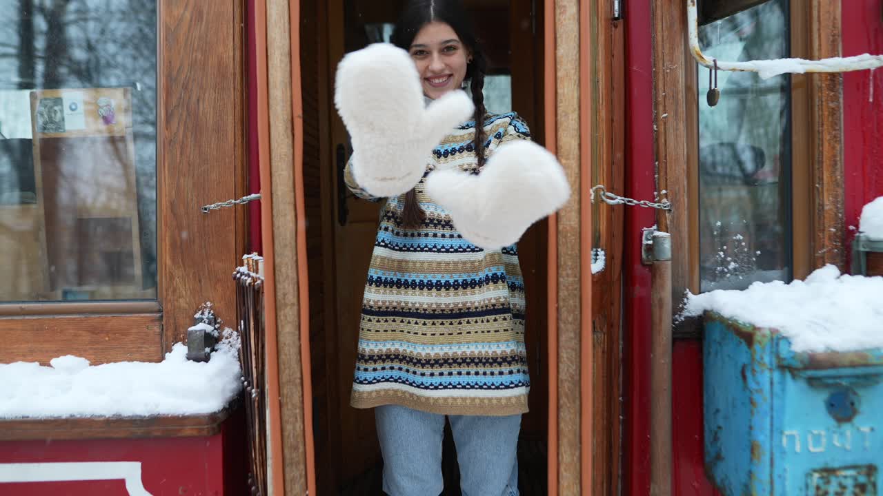 una adolescente sonriendo frente a una puerta de madera en invierno