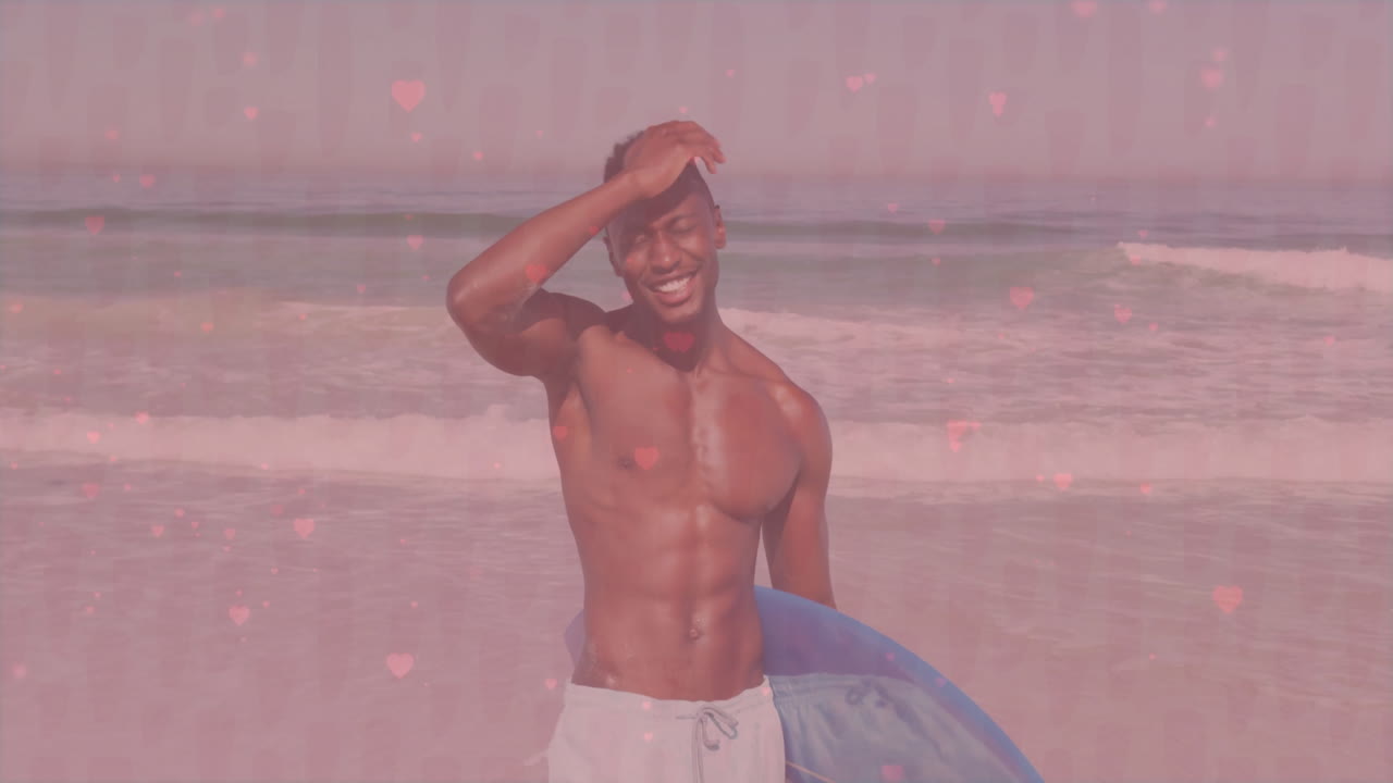 Man smiling and holding surfboard on beach with pink heart animation overlay