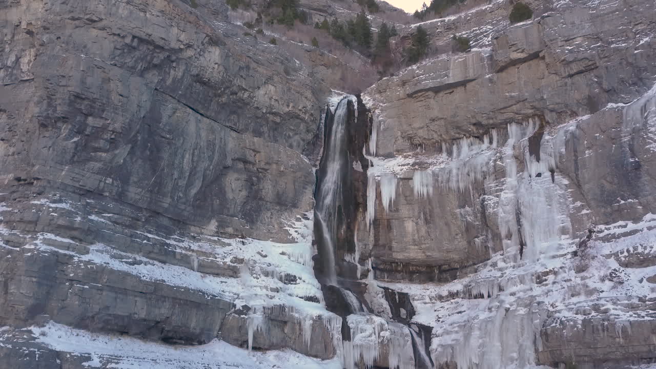 una cascada de alta montaña con agua congelada a los lados - dolly in