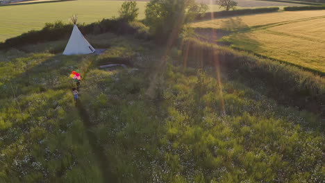 drone shot of two female friends camping at music festival running through field with balloons