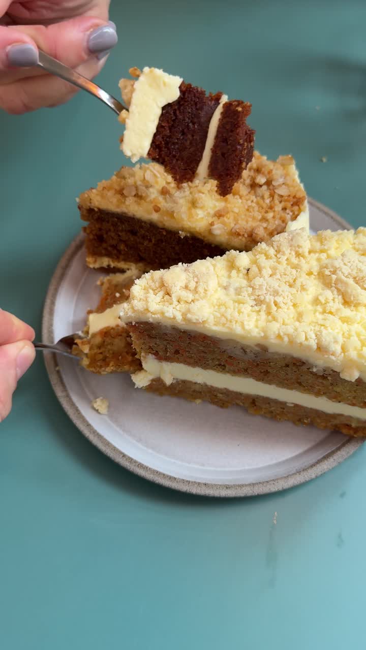 Layered cake slices on a plate as hands use forks to take bites. Vertical UGC-style close-up cake. Phone shot in amateur, social-media-friendly style, this dessert scene feels warm, casual