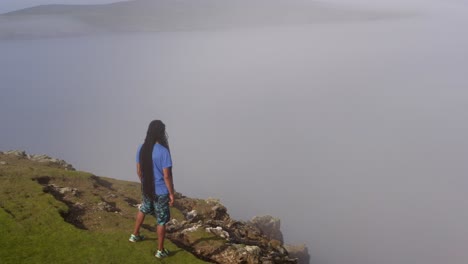 man gazing into foggy horizon, standing on cliff