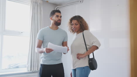 couple buying house for first time looking at house survey in room to be renovated