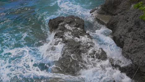 Durante-El-Día,-El-Agua-Azul-Profundo-Es-Visible-Cuando-Choca-Contra-La-Costa-Rocosa,-Las-Crestas-Blancas-Y-El-Rocío-Creado-Por-El-Impacto-En-Cámara-Lenta-Brindan-Una-Imagen-Impresionante-De-La-Fuerza-Del-Océano